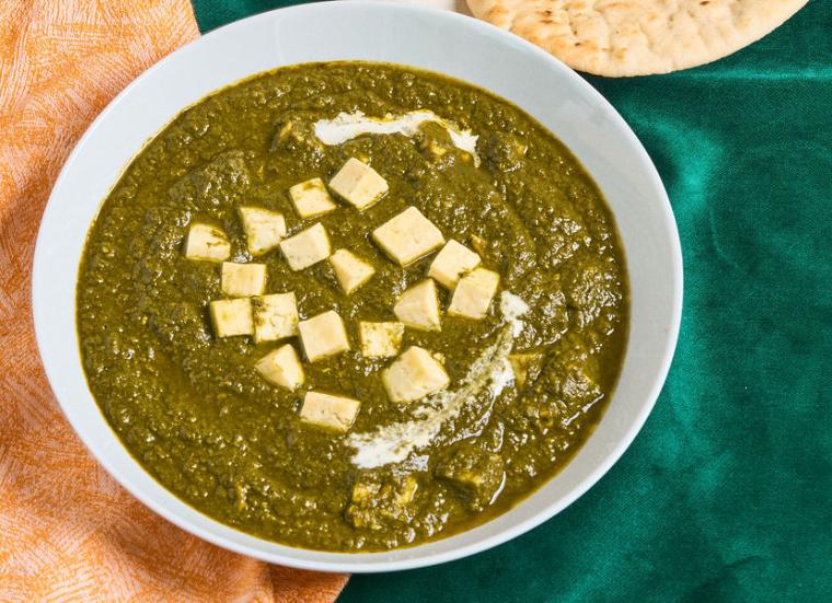 Bowl of Palak Paneer with orange napkin and naan