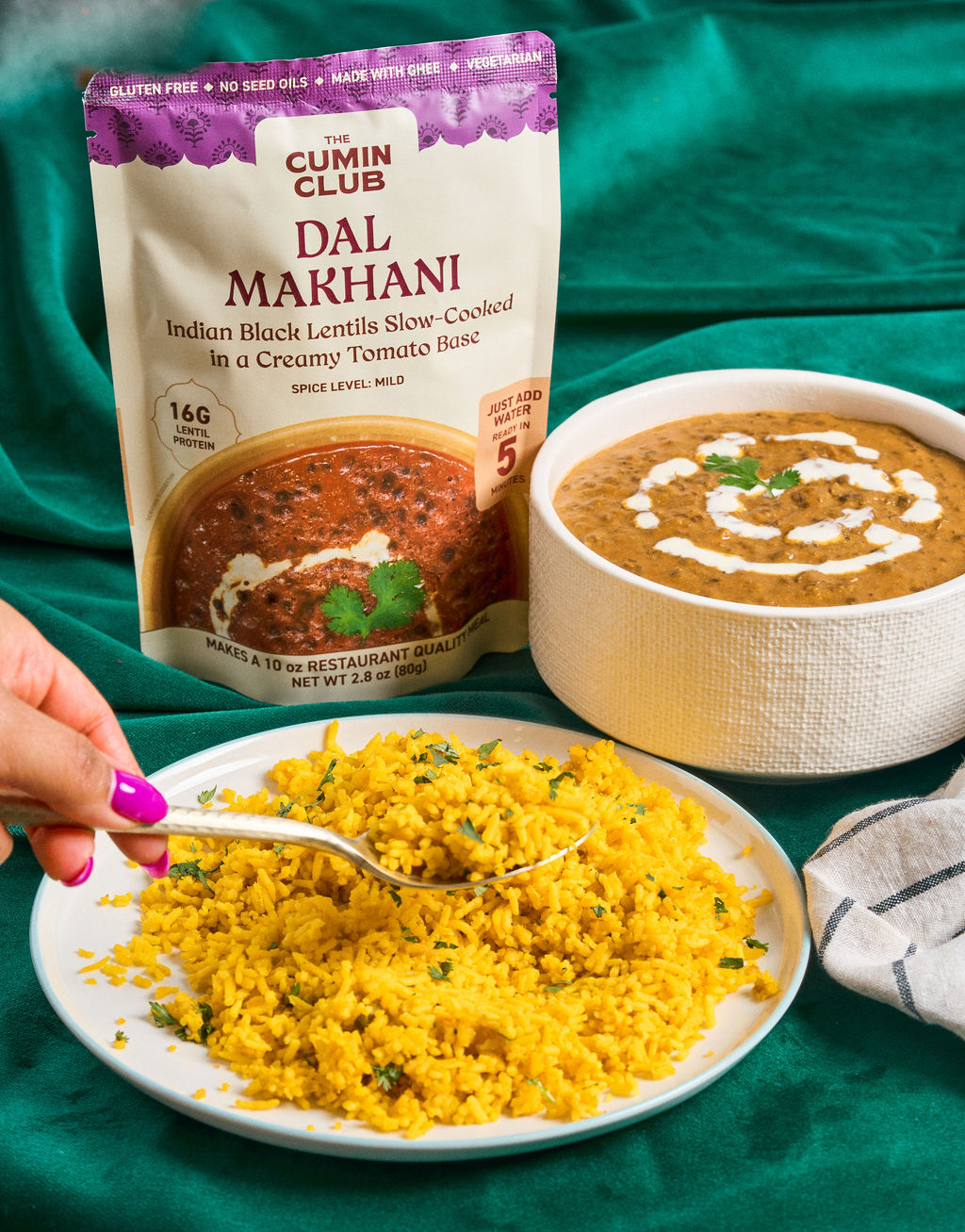 Dal Makhani pack beside a bowl of dal on a green backdrop