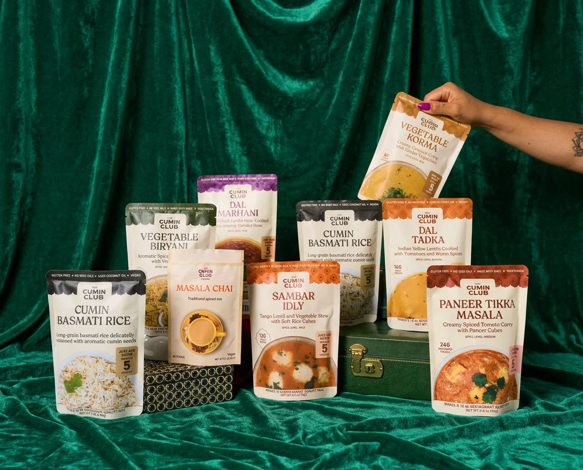Nine Cumin Club packs arranged on a green velvet backdrop